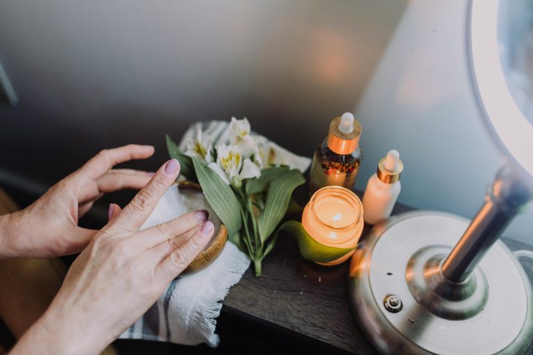 Relaxing skincare scene with hands, candles, and natural products for a soothing experience.